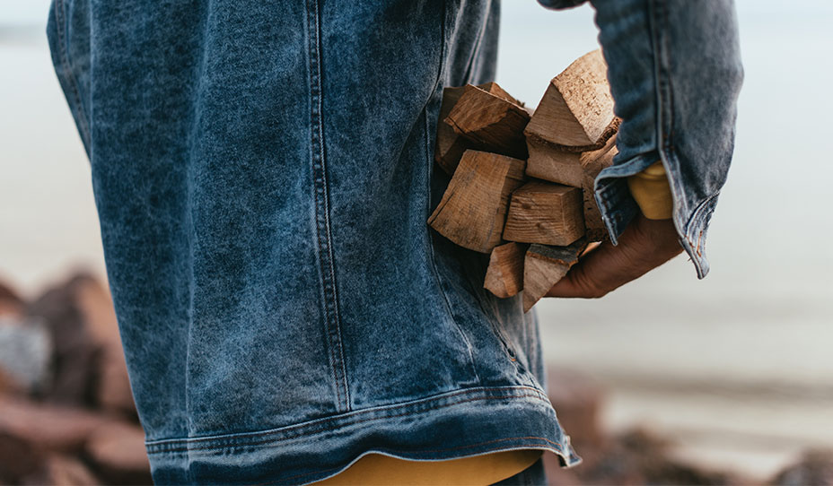 Person wearing a jean jacket carrying firewood